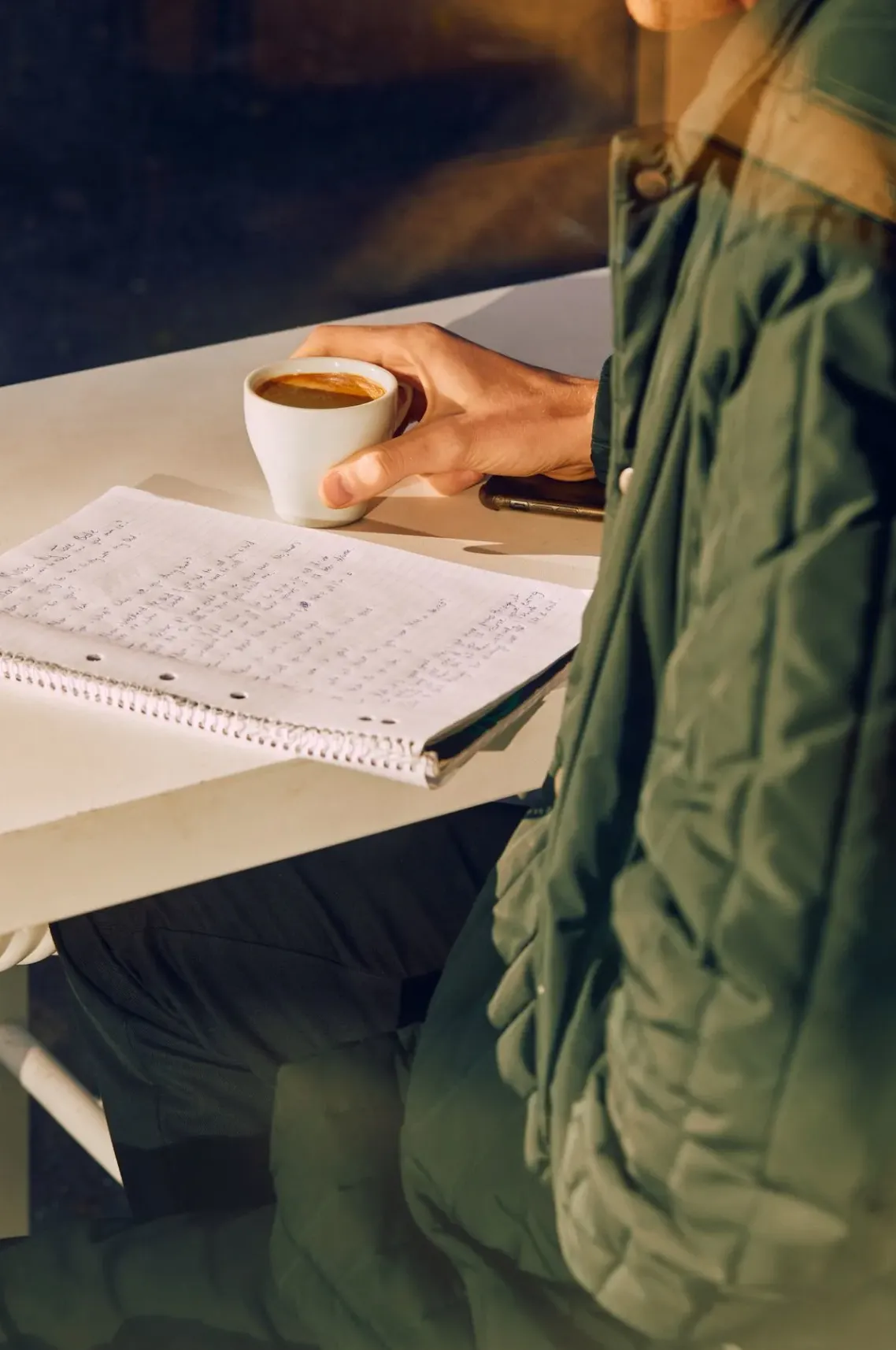 Hand holding a coffee over a notebook of figures
