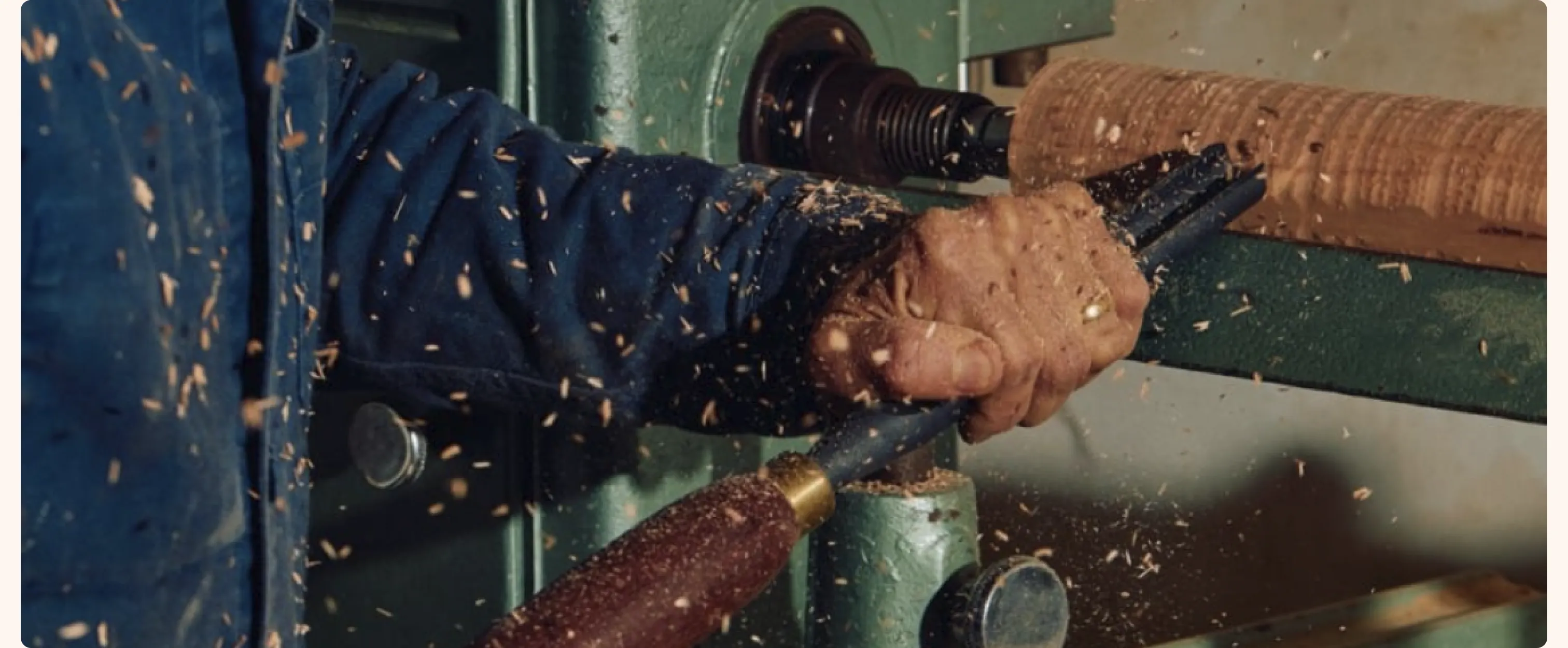 Craftsman turning wood on a lathe as shavings fly